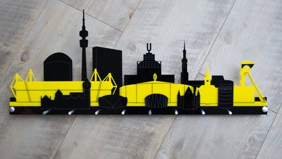 Dieses Schlüsselbrett zeigt die Skyline von Dortmund im Schwarzgelb des BVB. 3 Schichten Acrylglas bilden entweder ein schwarzgelbschwarz oder gelbschwarzgelb. Es gibt 8 Möglichkeiten etwas aufzuhängen. Die Aufhängung ist aus Aluminium.