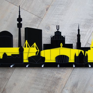 Dieses Schlüsselbrett zeigt die Skyline von Dortmund im Schwarzgelb des BVB. 3 Schichten Acrylglas bilden entweder ein schwarzgelbschwarz oder gelbschwarzgelb. Es gibt 8 Möglichkeiten etwas aufzuhängen. Die Aufhängung ist aus Aluminium.